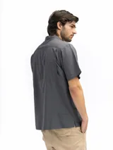 Camisa negra de manga corta con cuello clásico, cierre frontal con botones y bolsillo de parche en el pecho.