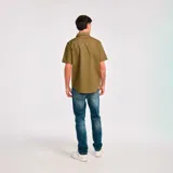 Camisa de manga corta color verde oliva con dos bolsillos de parche en el pecho con cierre de solapa y botón. Logo de Caterpillar bordado en la solapa del bolsillo izquierdo. Corte recto y cierre frontal con botones.