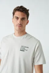 Remera de hombre color gris claro con estampado frontal con la frase "Art Music Cities & People" y el logo de la marca Brookfield.