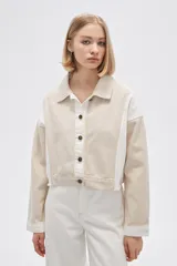 Campera corta de algodón color beige con detalles en blanco, de manga larga y cierre frontal con botones.