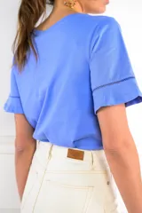 Remera blanca de algodón con cuello redondo y mangas cortas con volado y detalle de puntilla calada.