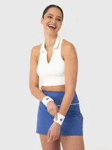 Top blanco con diseño cuello polo, corte cropped, sin mangas y espalda deportiva. Ideal para jugar pádel o tenis.