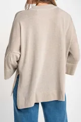 Sweater color cobre brillante, de tejido de punto con lurex, corte oversize, cuello redondo y mangas 3/4 con volados.