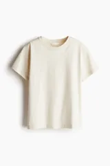 Remera color crema de algodón, corte holgado, con cuello redondo y mangas cortas.