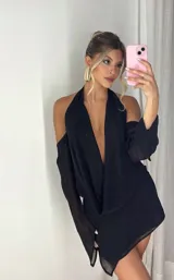 Minivestido negro con escote halter pronunciado y mangas largas con hombros descubiertos.