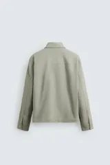 Sobrecamisa color arena de corte relaxed fit, confeccionada en tejido con mezcla de algodón. Tiene cuello solapa, manga larga con puños abotonados, bolsillos de plastrón con solapa en el pecho y bolsillos laterales en la costura de la cadera. El cierre es frontal con cremallera.