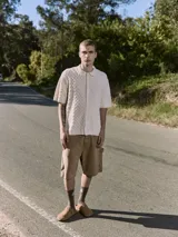 Polo de hombre color crema, tejido de punto cable, con cuello tipo polo, manga corta y cierre con botones.