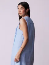 Vestido blanco de algodón y rayón, marca Dash. Cuello a la base, sin mangas y abertura central con botones. Delantera con detalle plisado y laterales con bolsillos.