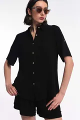 Camisa negra de manga corta con botones y cuello clásico.
