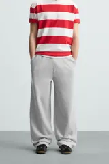 Pantalón jogger wide fit negro confeccionado en tejido de algodón con interior rizo. Pernera ancha, cintura elástica ajustable con cordón interior, bolsillos laterales y bolsillo trasero de plastrón.