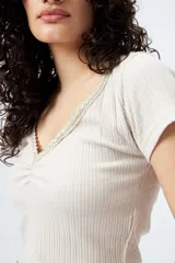 Remera corta negra de punto acanalado con escote en V fruncido y puntilla en el borde.