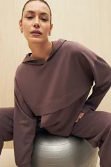 Canguro marrón con capucha, corte amplio y detalle de recorte frontal.