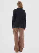 Buzo tejido color blanco, con cuello subido tipo polera, diseño oversized y largo con pequeños cortes laterales.