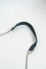 Cartera bandolera azul con tachas plateadas en forma de estrella, correa de cadena plateada y asa corta de cuero.