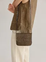 Cartera bandolera marrón con textura tipo piel de cocodrilo, solapa con cierre imantado y correa fina regulable.