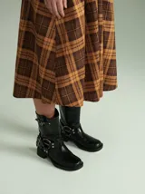 Botas cortas de cuero marrón con textura, hebillas ajustables, apliques circulares y punta cuadrada.