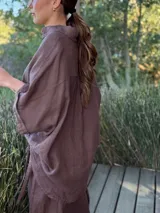 Camisa marrón de lino con botones blancos, corte holgado y mangas cortas.