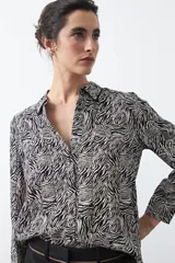 Camisa de manga larga con estampado de cebra en blanco y negro, confeccionada en tejido liviano con caída fluida. Presenta cuello clásico y cierre frontal abotonado.