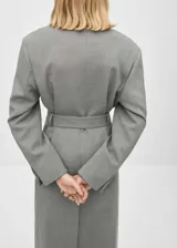 Abrigo gris con cuello con solapa, diseño cruzado y cinturón con hebilla.