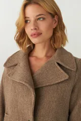 Chaquetón marrón de lana con cuello, abrochadura simple con botón en el cuello, bolsillos ojal y detalle de martingala en mangas.