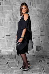 Vestido negro con capa de gasa, hombros descubiertos y terminación asimétrica. Detalles de brillos en los tirantes.