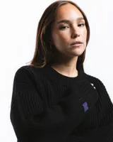 Sweater negro de punto con cuello redondo y corte holgado. Diseño con motivo de zurcido en la manga izquierda.