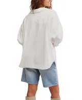 Camisa blanca de algodón con cuello clásico, manga larga y cierre frontal con botones. Tiene un bolsillo en el pecho y corte ligeramente entallado.