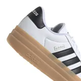 Championes Adidas VL Court Bold de cuero blanco con las tres tiras laterales en negro, puntera de gamuza beige y suela de plataforma color caramelo.
