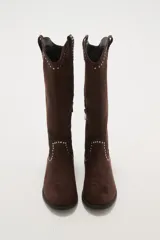 Botas texanas negras de caña media, confeccionadas en gamuza. Presentan un diseño de estilo western con detalles de tachas metálicas plateadas decorando el borde superior y el contorno del empeine. Tienen un taco bajo y punta ligeramente afilada.