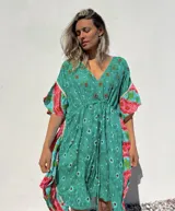Túnica corta verde con estampado de flores rojas y detalles bordados. Mangas anchas con terminación en volados con estampado floral en tonos rosa y celeste.