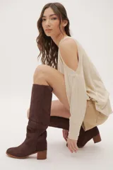 Bota de caña alta color beige, confeccionada en cuero gamuzado. Tiene taco de madera y puntera redondeada.