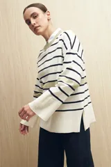 Sweater de rayas horizontales color crudo y marrón, con cuello redondo a contratono color beige, tajos laterales y mangas largas con puño ancho.