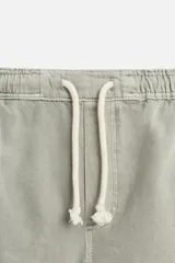 Bermuda color beige de denim de algodón, corte relaxed fit, con cintura elástica ajustable con cordón, bolsillos frontales y traseros.