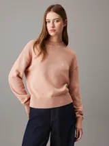 Sweater de punto color salmón, de corte relaxed, con cuello redondo y monograma bordado de Calvin Klein en el pecho.
