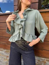 Blusa verde agua con cuello camisero con volados, mangas largas con puños elásticos y corte a la cintura.