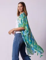 Kimono tejido con estampado abstracto en tonos verde, azul y blanco. Tiene mangas cortas amplias y terminación con borlas verdes en el ruedo.