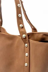Bolso tipo shopper color negro con apliques de tachas plateadas en los bordes y las asas.