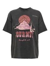 Remera negra con efecto gastado, cuello redondo y mangas cortas. Estampado frontal con diseño de montaña, sol y texto 'Journey Through the Wild'.