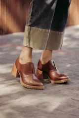 Zapatos de cuero color marrón con puntera fina, detalle de textura en el empeine, diseño slip-on y suela dentada.