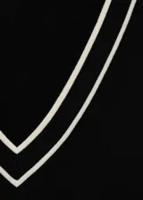 Jersey de punto fino color negro con cuello de pico y ribetes en contraste blanco en el cuello y puños. Diseño recto y manga larga.