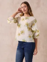 Blusa de gasa color crema con estampado de flores amarillas, de la marca Sioni. Tiene mangas 3/4 con volados y cuello redondo.