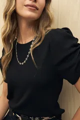 Top blanco de mangas cortas abullonadas y cuello redondo. Tejido de punto acanalado.