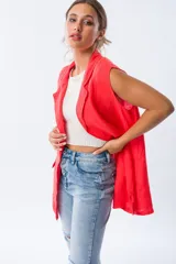 Chaleco largo color rojo coral, sin mangas, con solapas y bolsillos laterales. Confeccionado en lino.