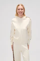Sweater color crema con capucha y cordones, de tejido de punto, con mangas largas y detalle de franja con estampado animal en mangas y laterales.