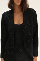 Blazer negro con estampado de lunares blancos, de corte recto y solapas clásicas.