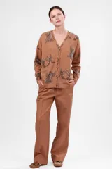 Cárdigan color marrón claro con estampado de aves, lunas y estrellas. Tiene escote en V, cierre con botones y bolsillos delanteros.