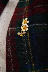 Broche dorado con forma de abeja con alas de strass colgando de un ramillete de flores blancas con centro amarillo.