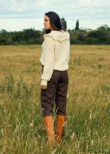 Sweater color crema tejido a crochet con lana merino, cuello alto con volados y mangas largas.