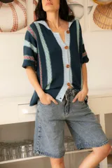 Camisa tejida de algodón a rayas verticales en tonos azul, celeste y rosa, con botones al frente y mangas cortas.