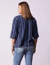 Blusa de algodón con estampado a rayas verticales en tonos celeste, rosa y blanco. Tiene cuello redondo con escote en V y abertura con botones de madera. Las mangas son 3/4 con aplique de botones.